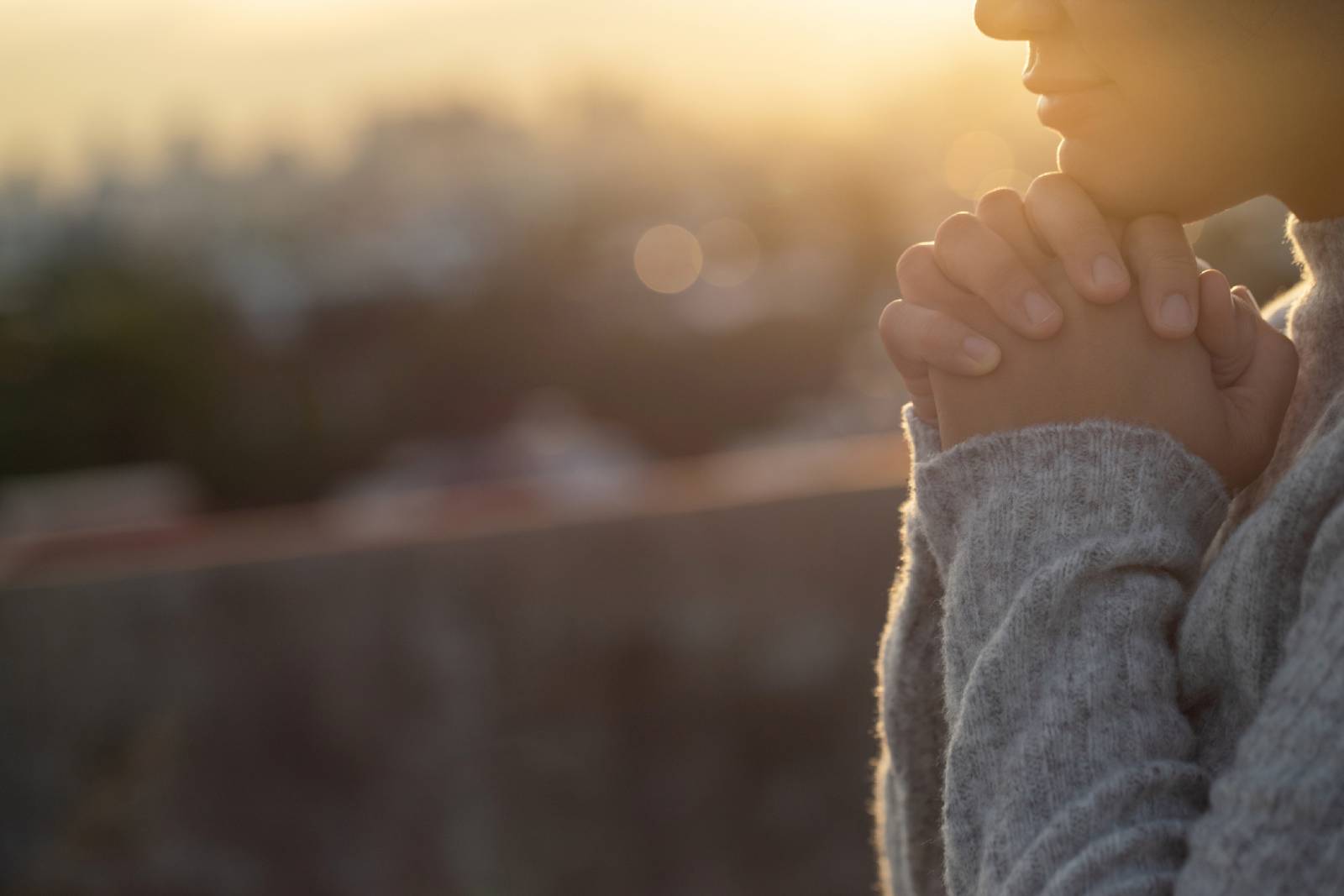 Junge Frau mit verschränkten Händen bei Sonnenaufgang | Credit: iStock.com/Kamonwan Wankaew