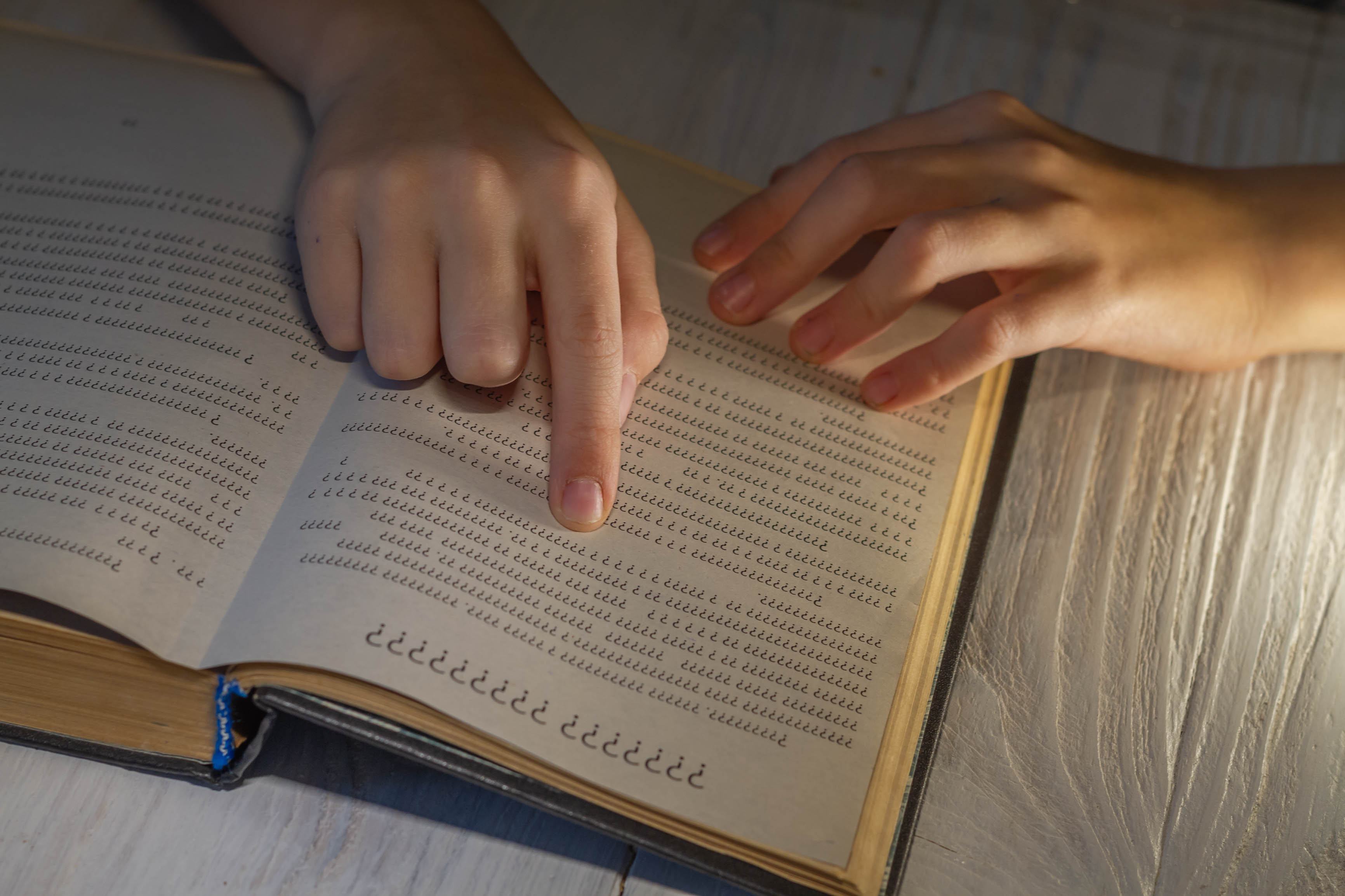 Ein Finger deutet auf eine Seite in einem Wörterbuch, die mit lauter Fragezeichen bedruckt ist