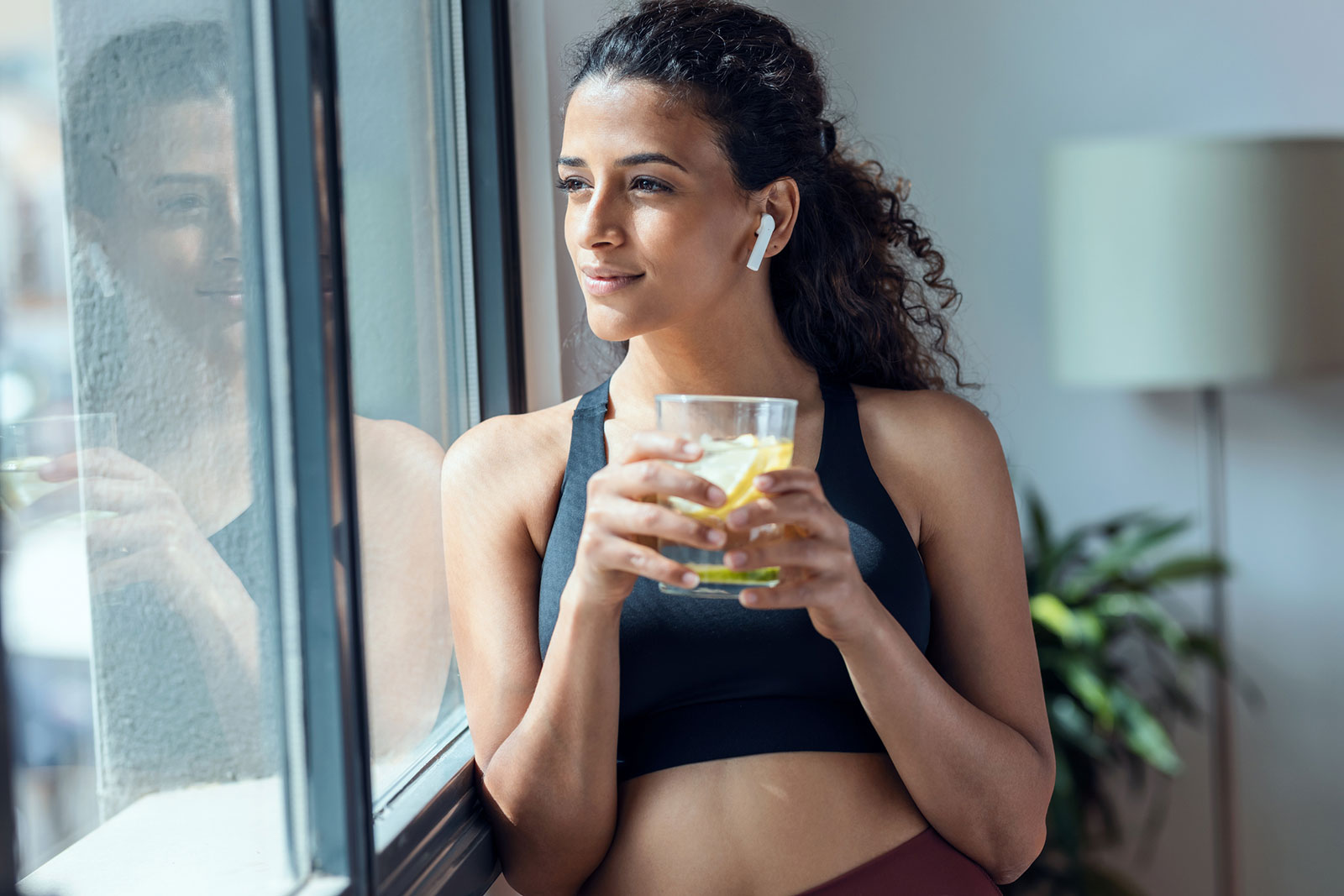 Frau in Trainingskleidung trinkt ein Glas Wasser | Credit: iStock.com/nensuria