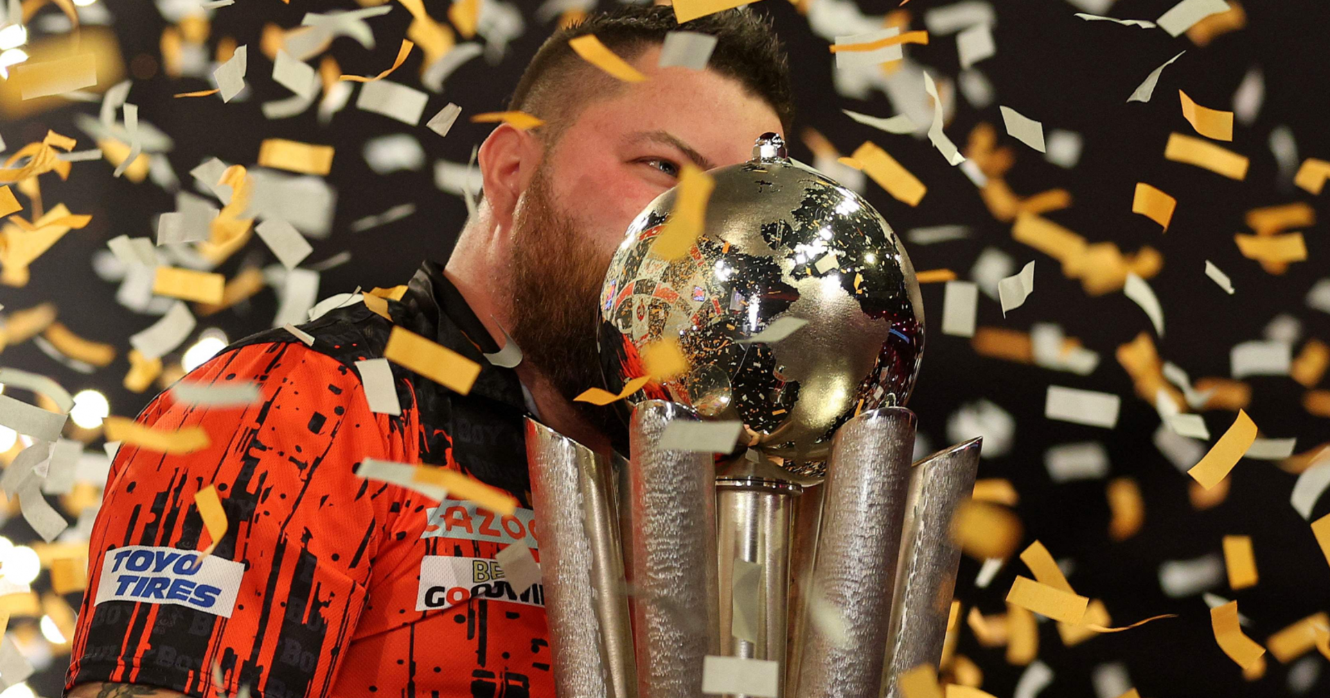 Der Darts-Spieler Michael Smith küsst, umschwirrt von einem Konfetti-Regen, die Siegestrophäe der Darts-WM