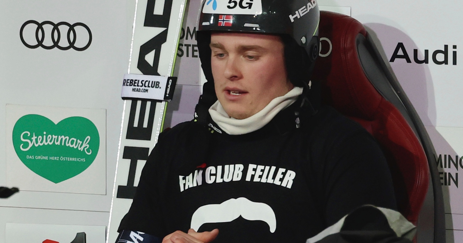 Der norwegische Skifahrer Atle Lie McGrath in einem schwarzen T-Shirt mit der Aufschrift "Fan Club Feller" auf dem Stuhl des Führenden in Schladming