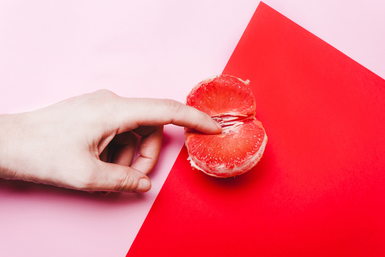 Frau hat einen Finger in einer Grapefruit