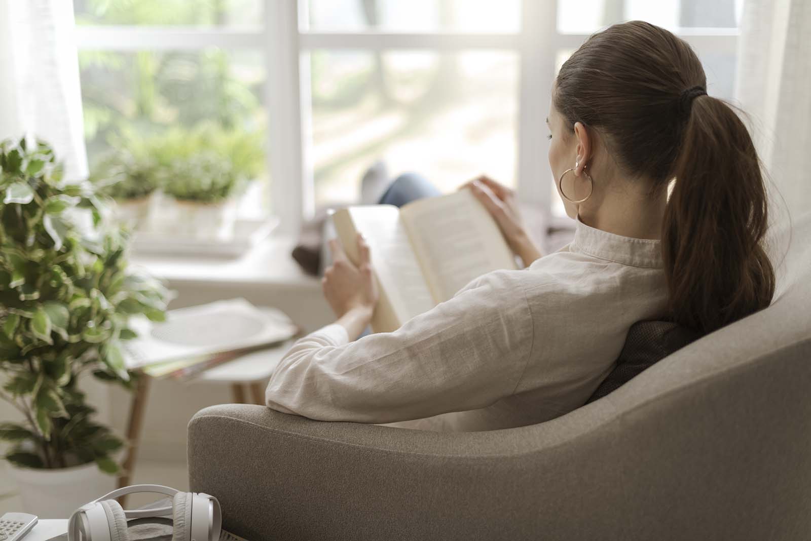 Frau sitzt im Sessel und liest | Credit: iStock.com/demaerre