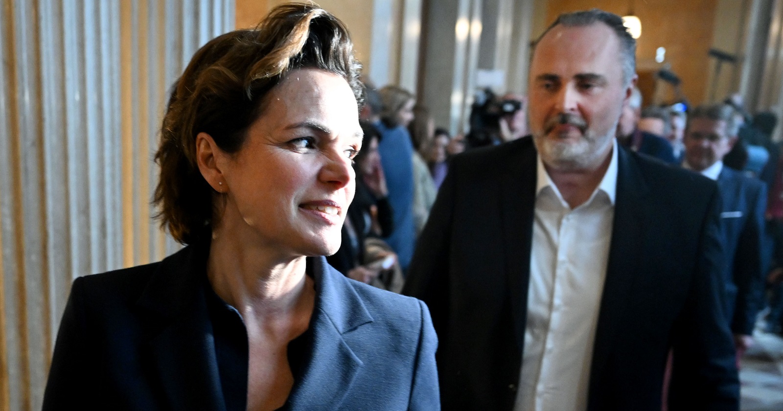 Pamela Rendi-Wagner in Großaufnahme im Gehen nach einem Termin. Hinter ihr folgt Hans-Peter Doskozil, im Hintergrund weitere Menschen.