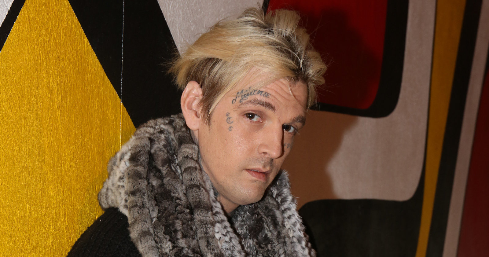 Aaron Cater mit Gesichtstattoo und leerem Blick.