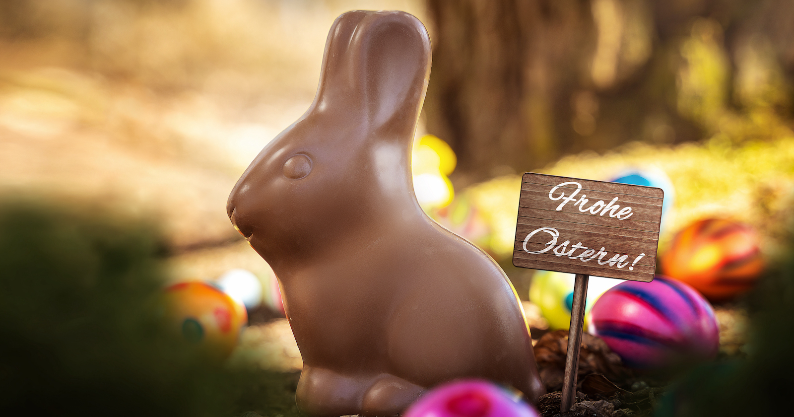 Ein Schoko-Osterhase und ein Schild, auf dem "Frohe Ostern" steht.
