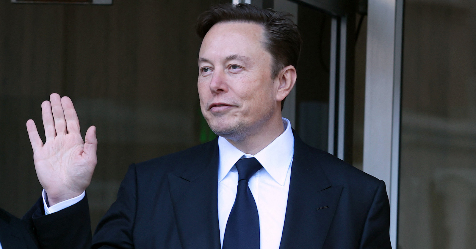 Elon Musk winkt Reportern zu.