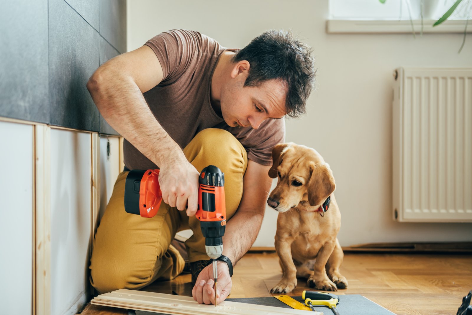Mann bohrt ein Loch in ein Holzbrett | Credit: iStock.com/Kerkez