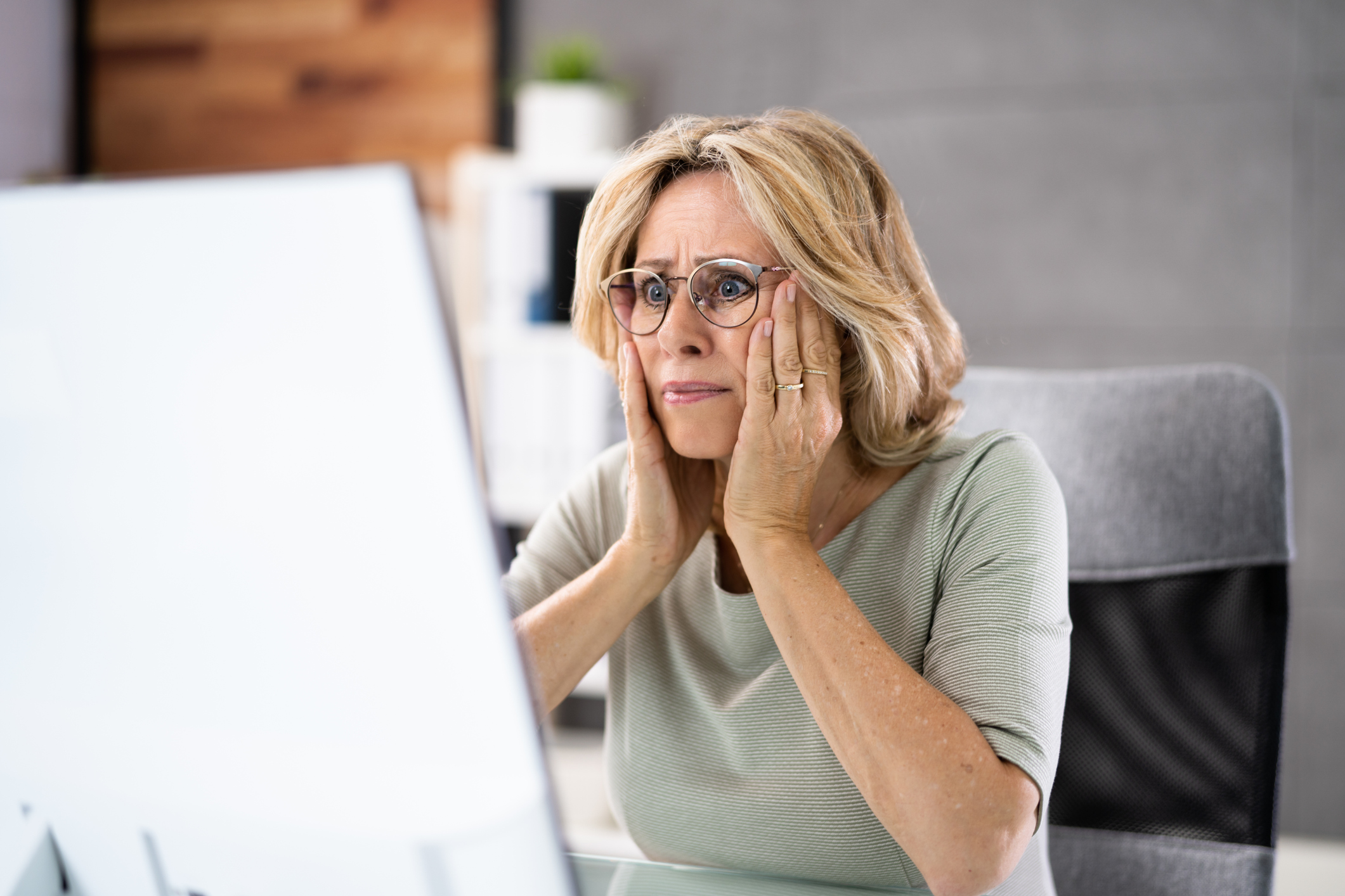 Ältere Frau erschrocken vor Laptop