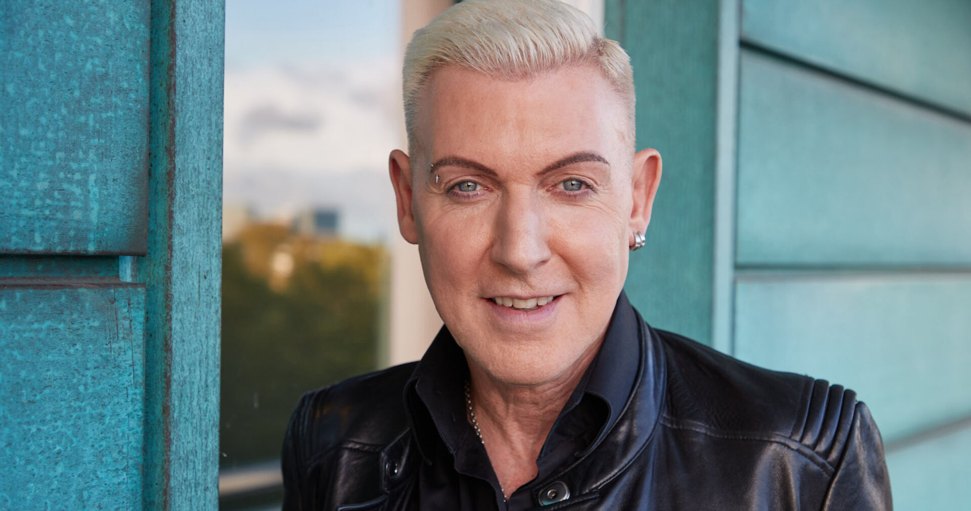 Ein Mann mit weiß gefärbten Haaren schaut in die Kamera