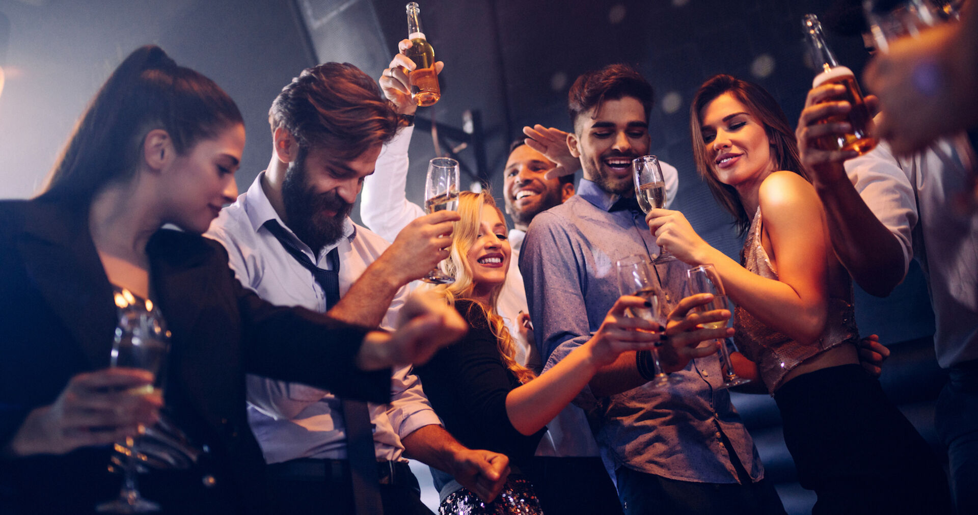 Partypeople mit Bier und Champagner beim Tanzen