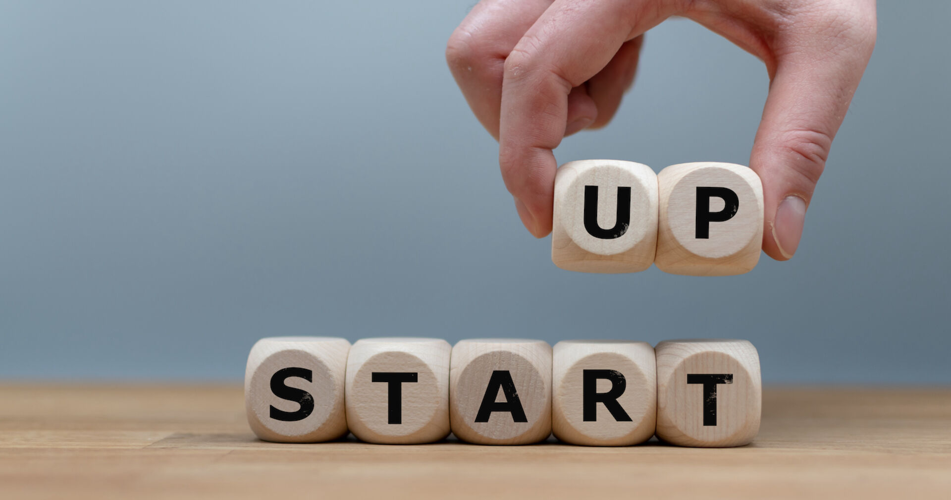 Hand von oben arrangiert Buchstaben aus Holz zuStart-Up