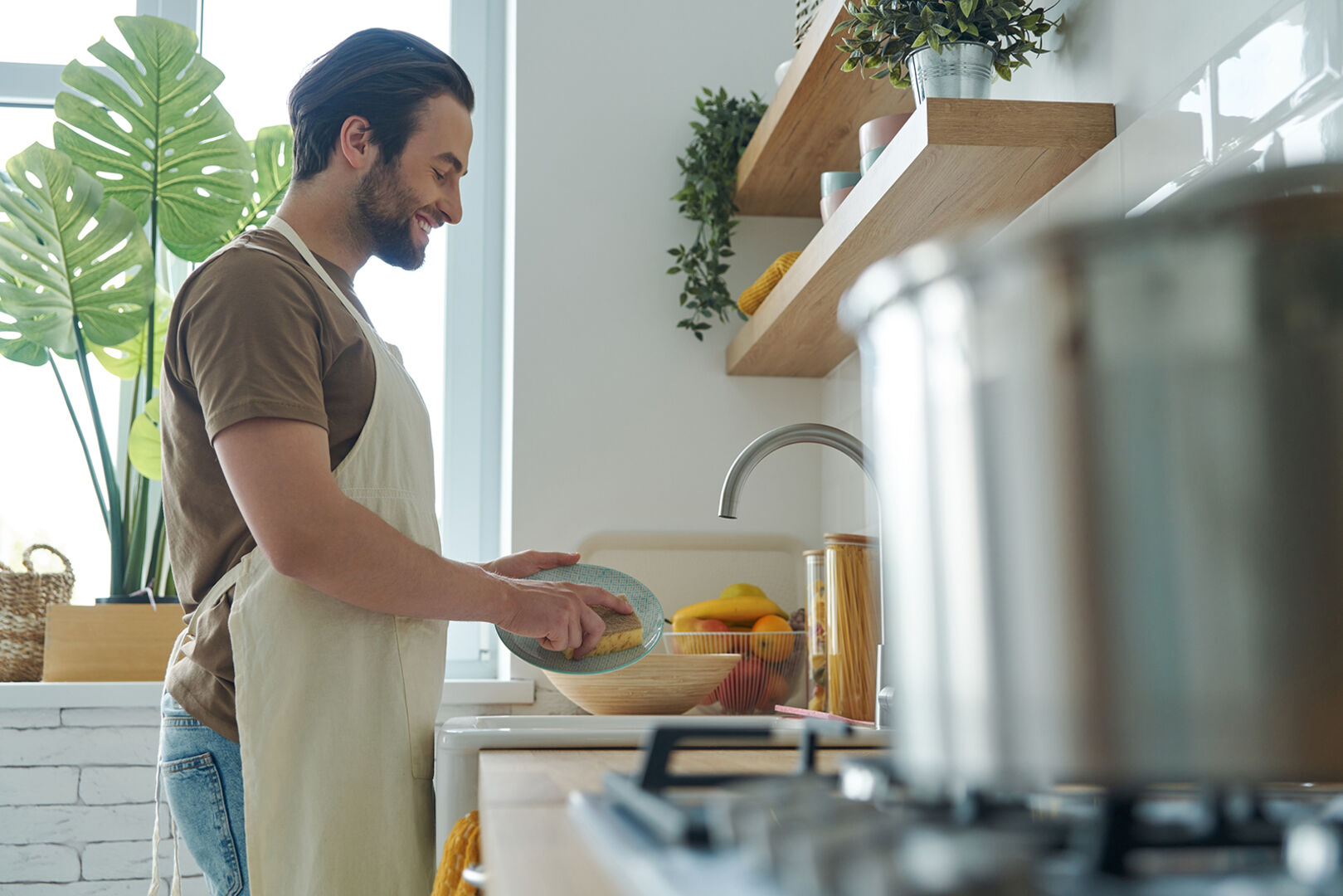 Mann wäscht Geschirr ab | Credit: iStock.com/g-stockstudio