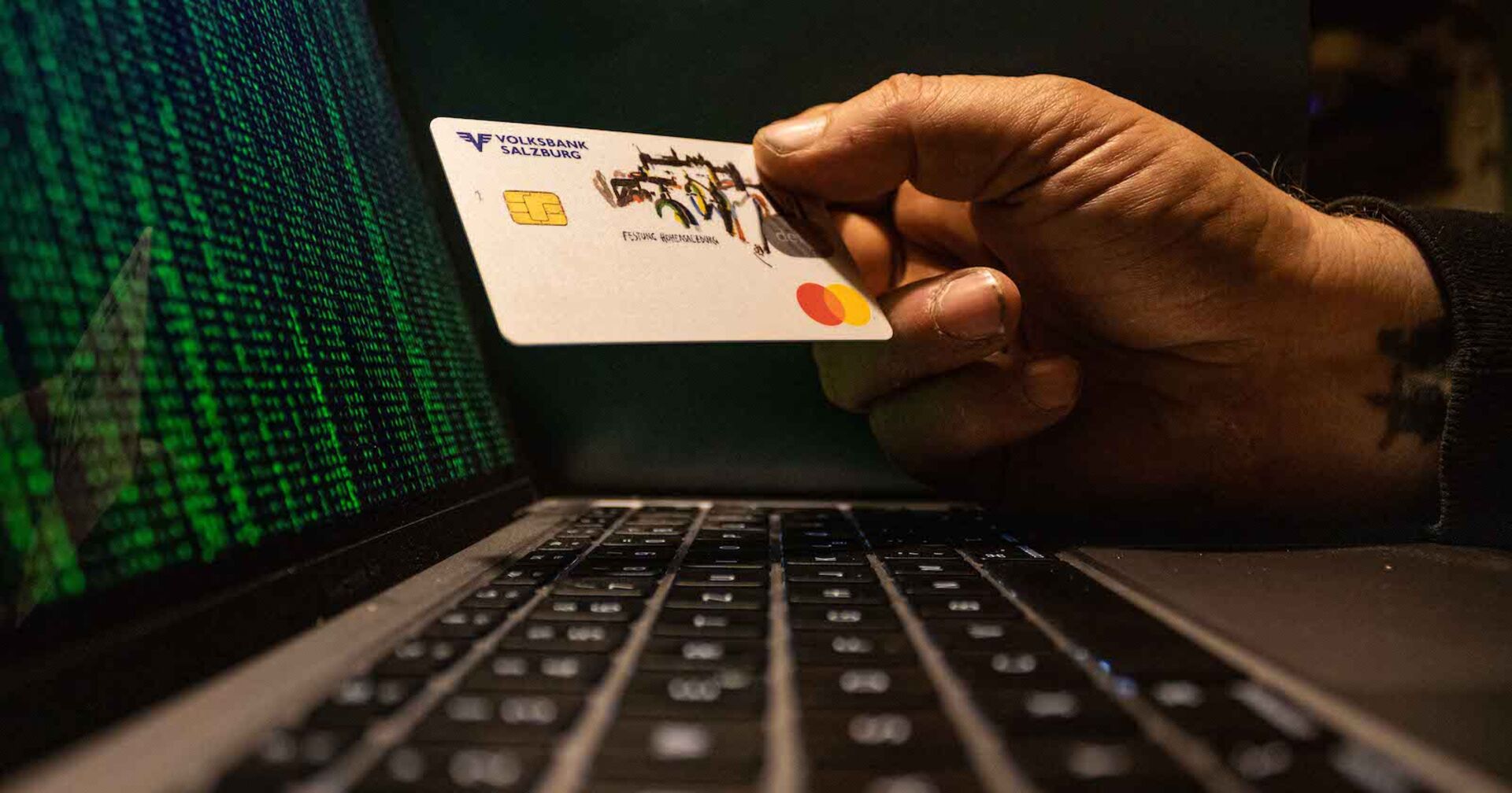 Hand eines Betrügers vor dem Laptop.