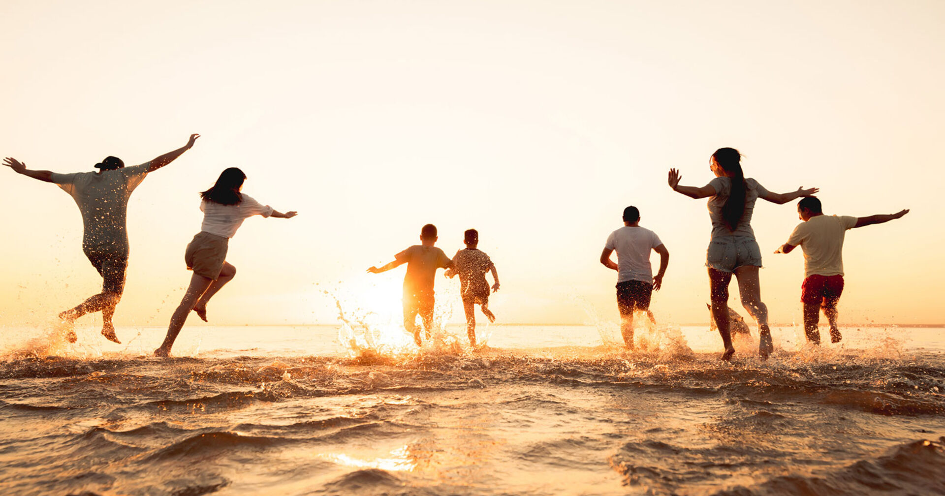 Gruppe junger fröhlicher Menschen läuft ins Meer | Credit: iStock.com/molchanovdmitry