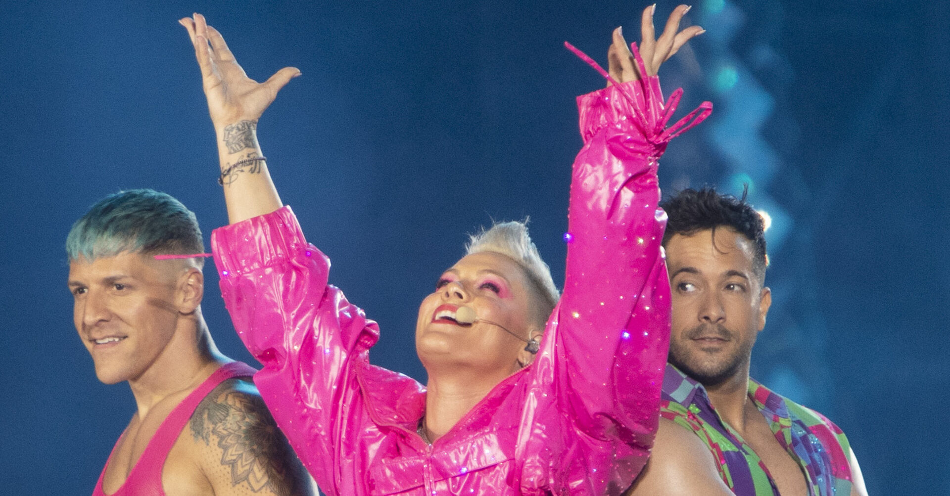 Eine Sängerin mit Mikrophon auf der Bühne und Tänzer neben ihr.