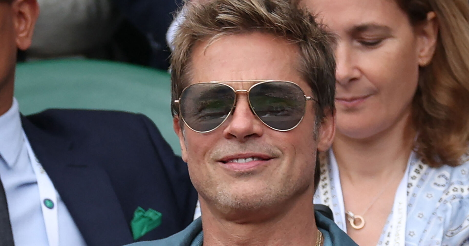 Ein Mann mit einer Sonnenbrille schaut bei einem Tennismatch zu.