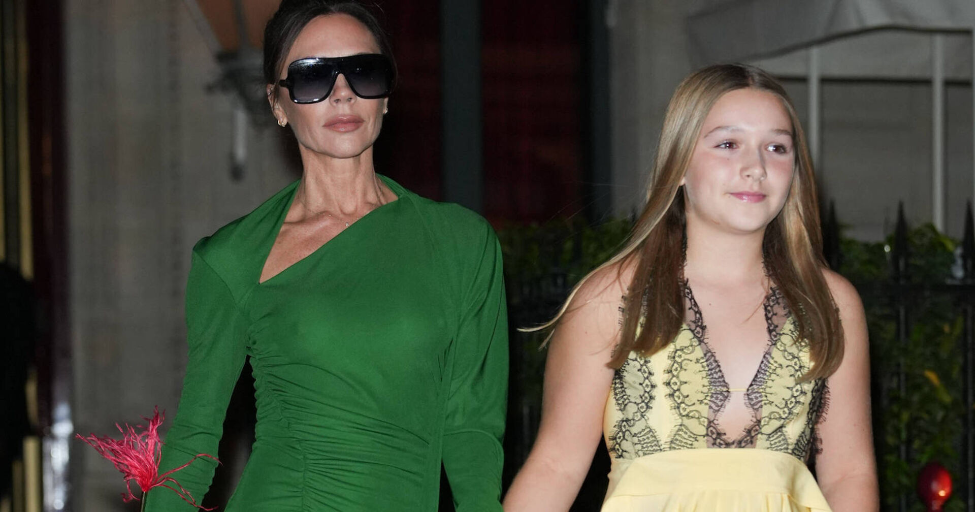 Eine Frau mit Sonnenbrille und grünem Kleid und ein Mädchen an der Hand.