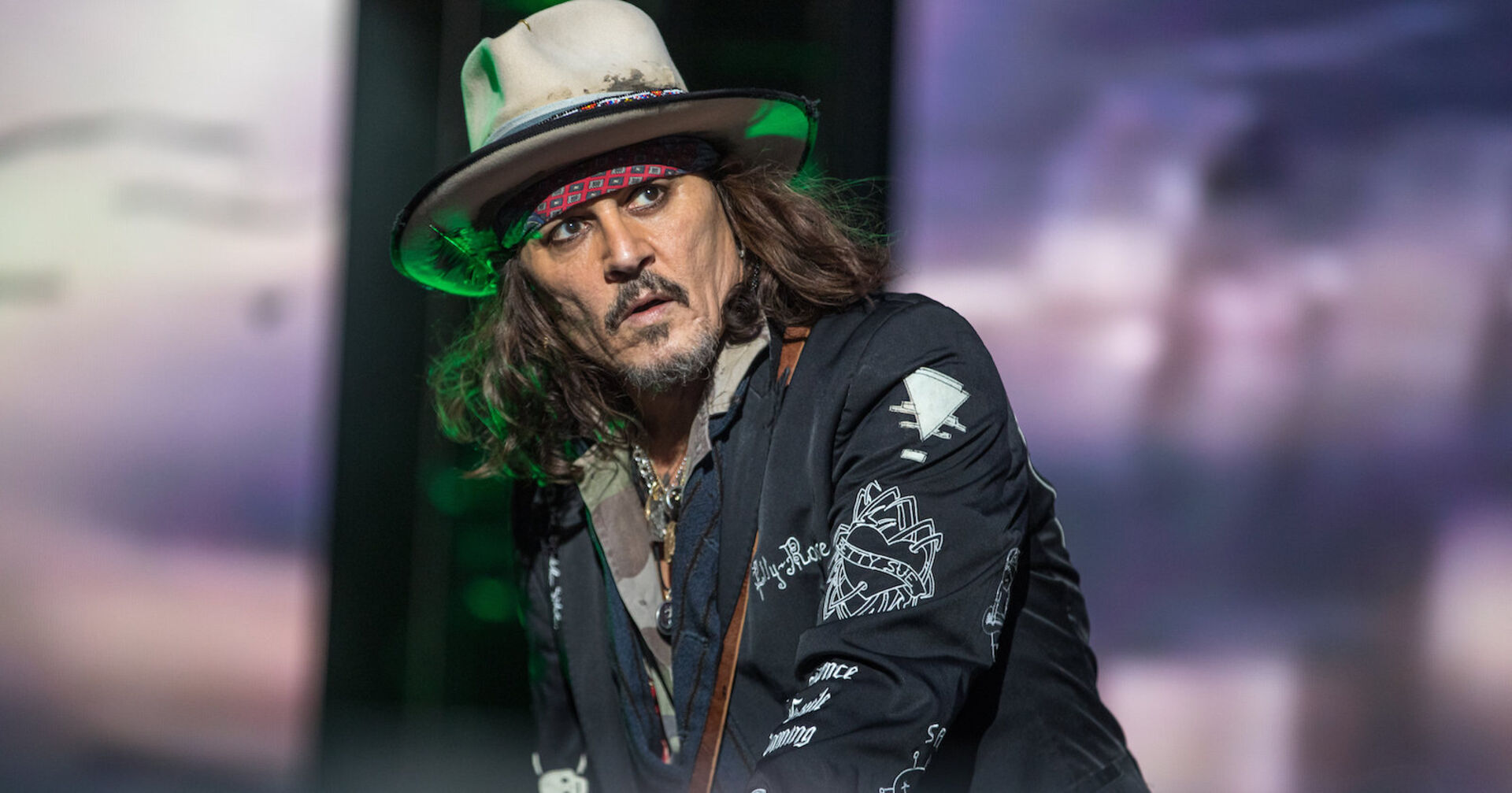 Ein Mann mit Bart und einem Hut steht auf einer Bühne.