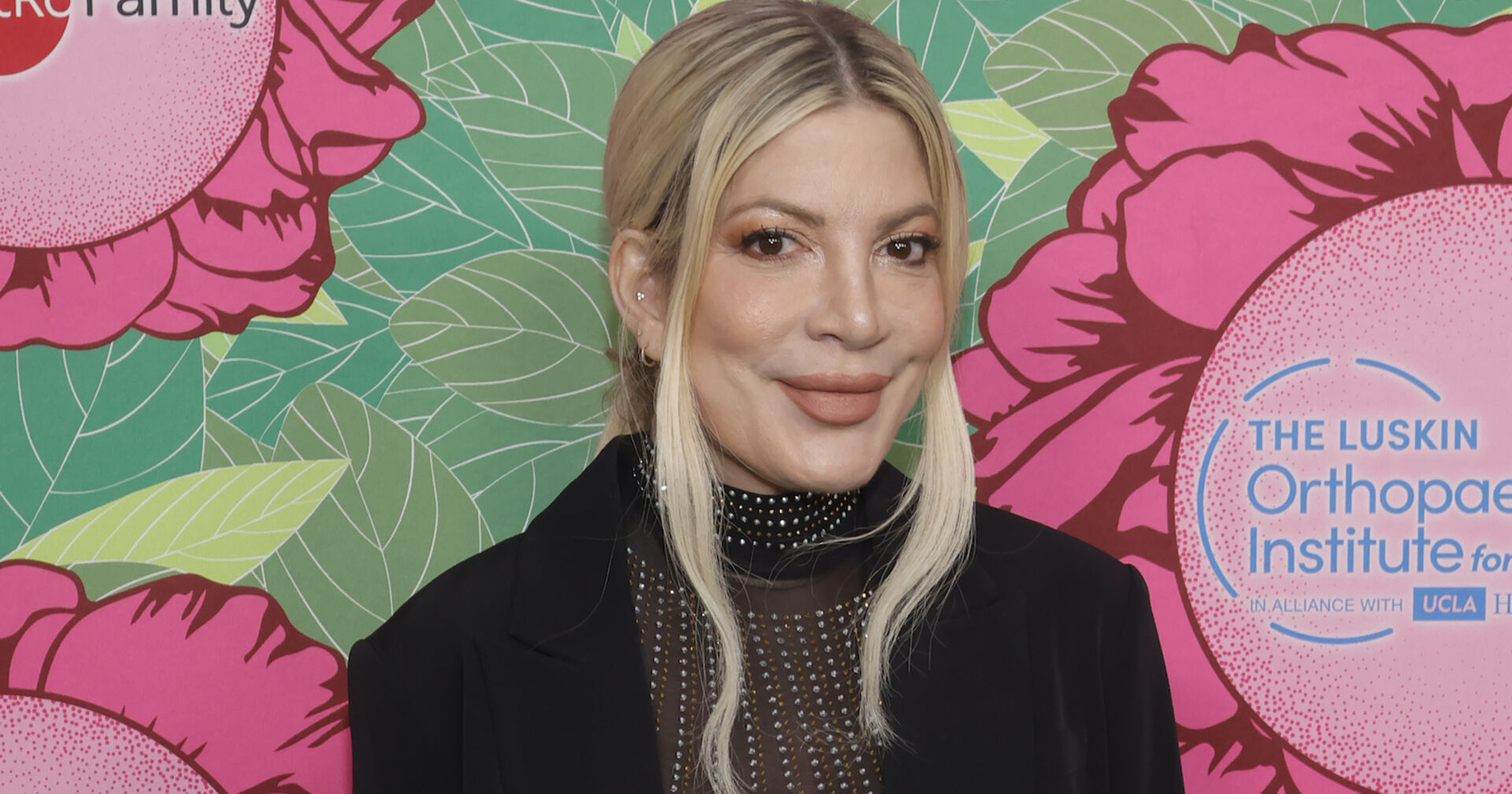 Eine blonde Frau steht vor einer bunten Wand.