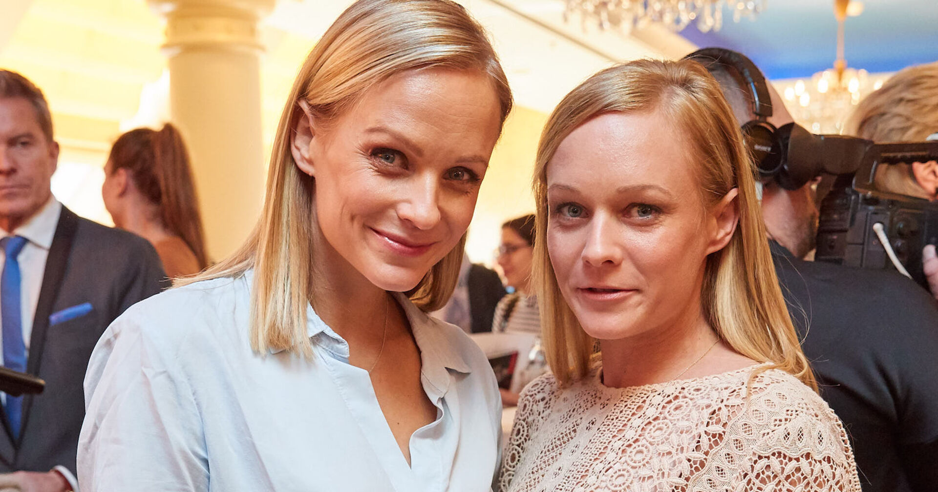 Zwei junge Frauen mit blonden Haaren lachen in die Kamera.