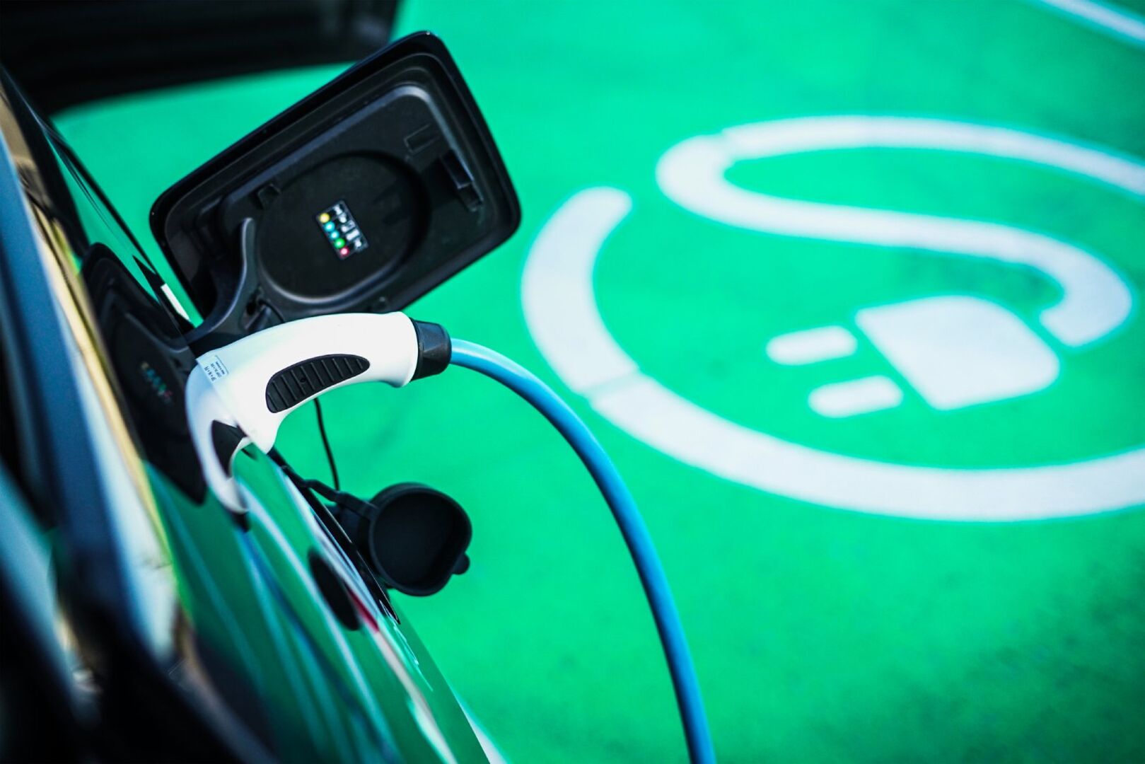 E-Auto steht auf grünem Ladeparkplatz | Credit: iStock.com/RS-Studios