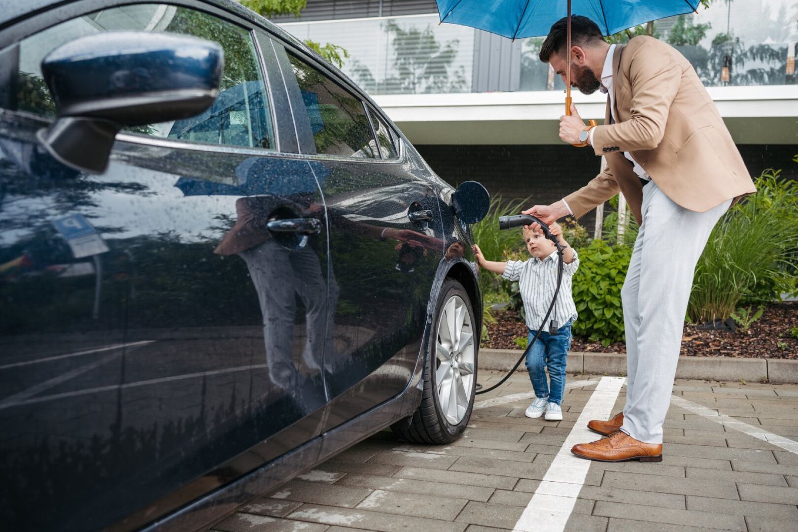Mann lädt E-Auto im Regen | Credit: iStock.com/Halfpoint