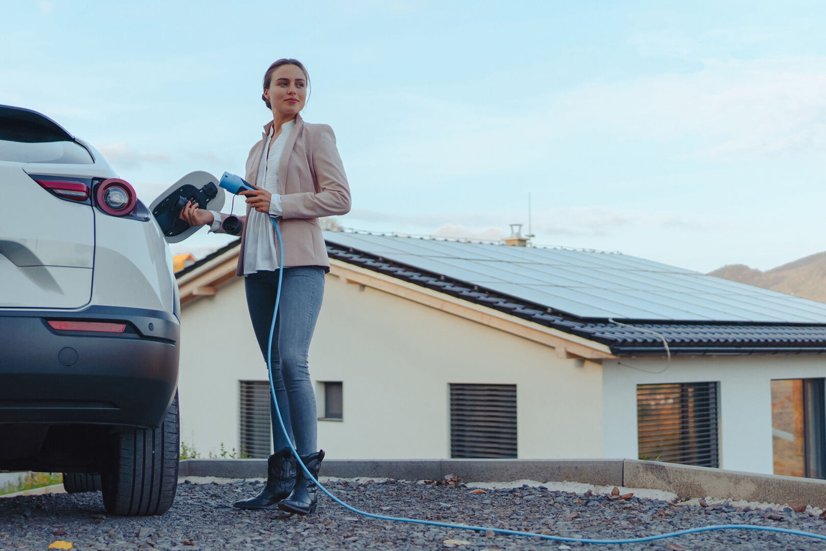 Frau lädt zuhause ihr E-Auto | Credit: iStock.com/Halfpoint