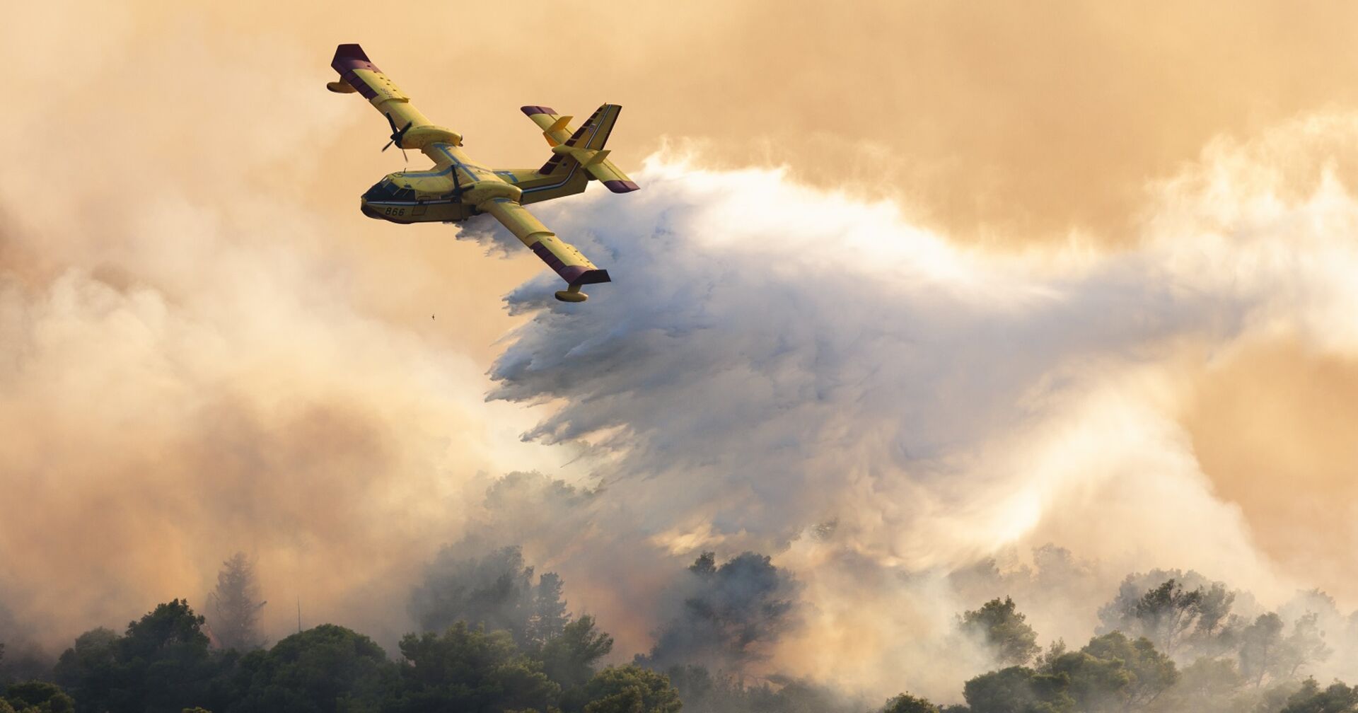 Ein Löschflugzeug leert seinen Wassertank über der brennenden Insel