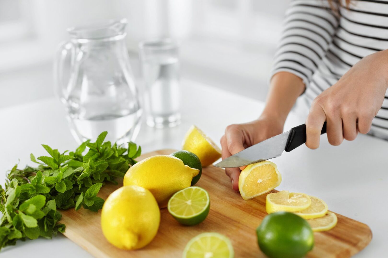 Frau schneidet Zitronen und Limetten | Credit: iStock.com/puhhha