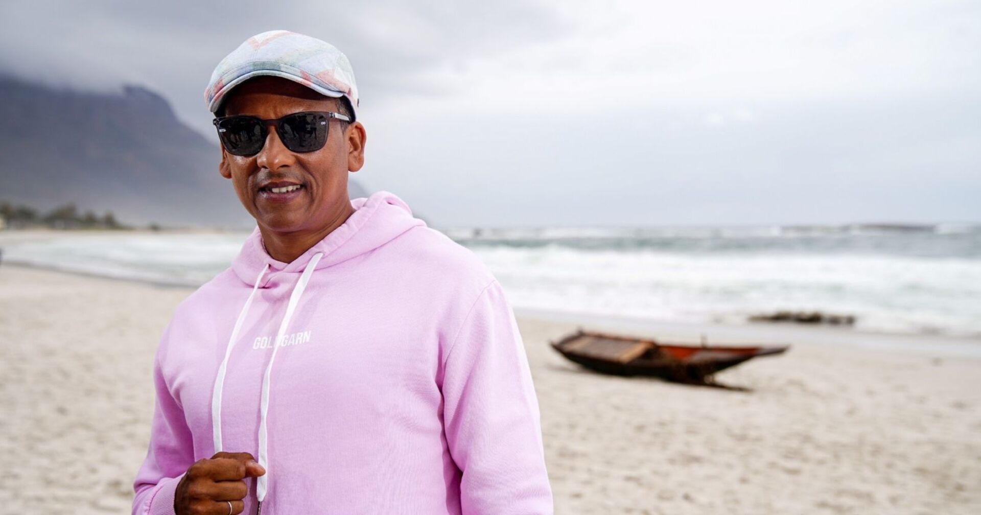 Xavier Naidoo mit rosa Pullover am Strand.