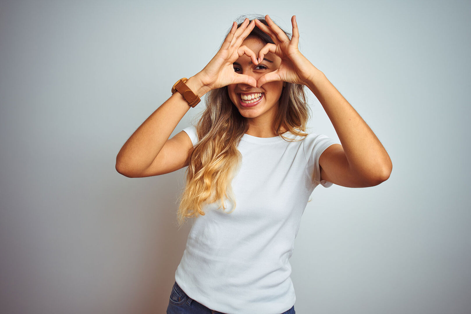 Junge Frau bildet mit den Händen ein Herz vor ihren Augen | Credit: iStock.com/AaronAmat