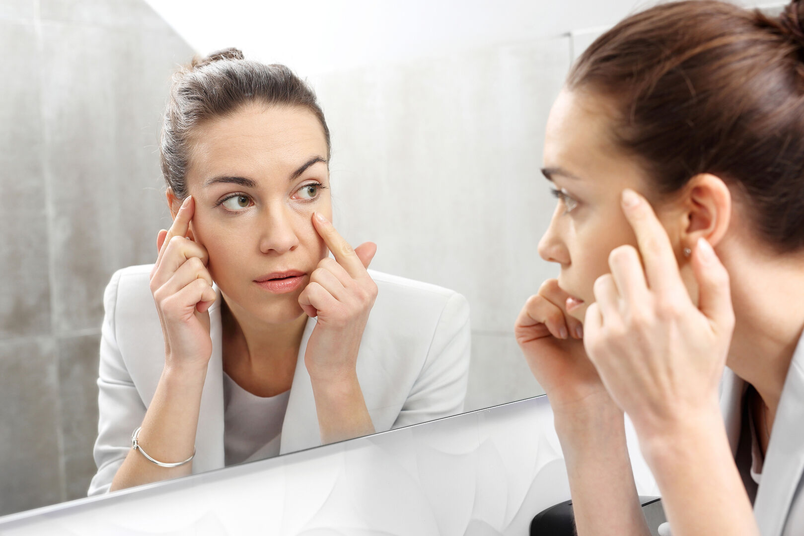 Frau schaut sich ihre Augen im Spiegel an | Credit: iStock.com/robertprzybysz