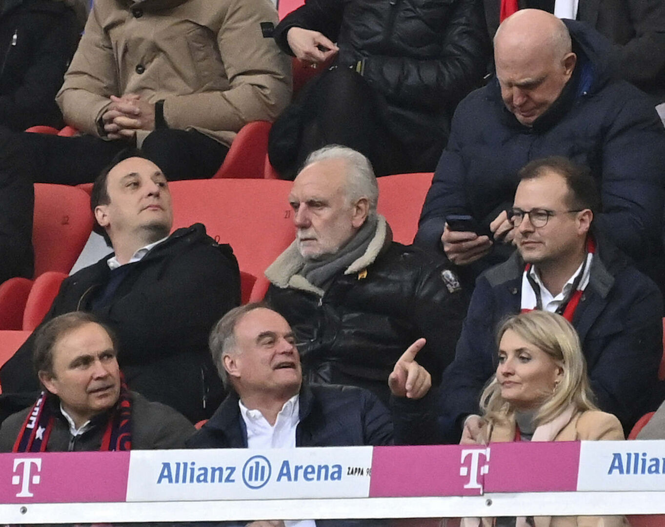 Franz Beckenbauer sitzt mit anderen Männern im Fußballstadion.