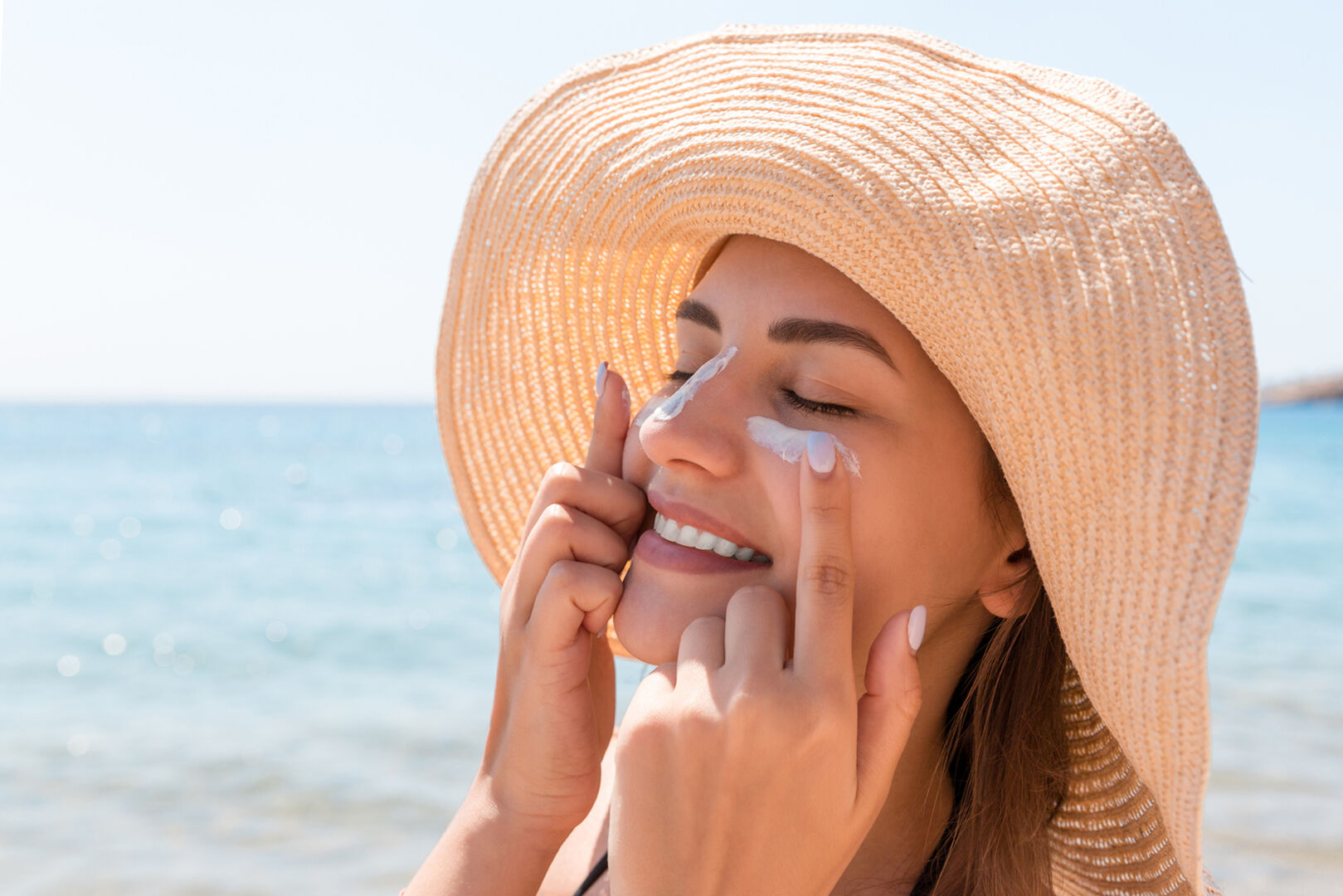 Frau cremt Gesicht mit Sonnenschutz ein | Credit: iStock.com/Mykola Sosiukin