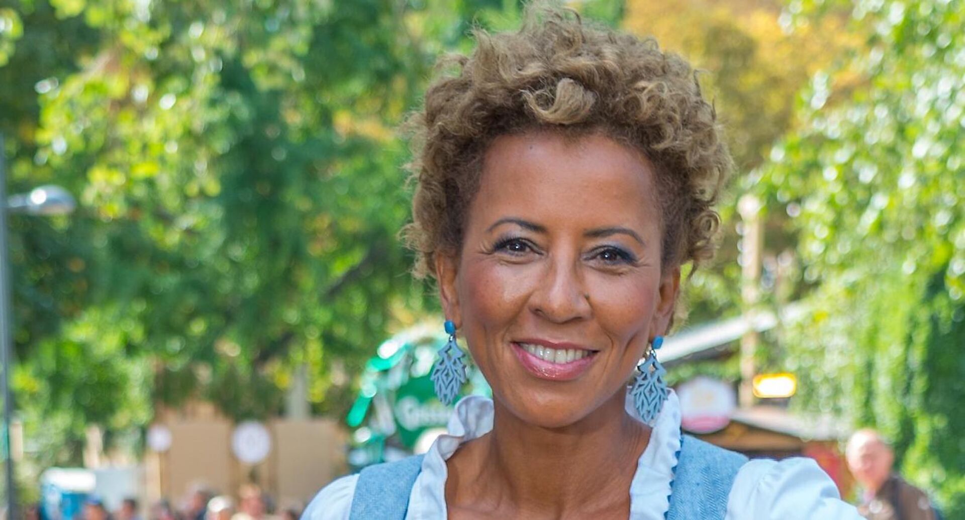 Arabella Kiesbauer vor einem begrünten Park