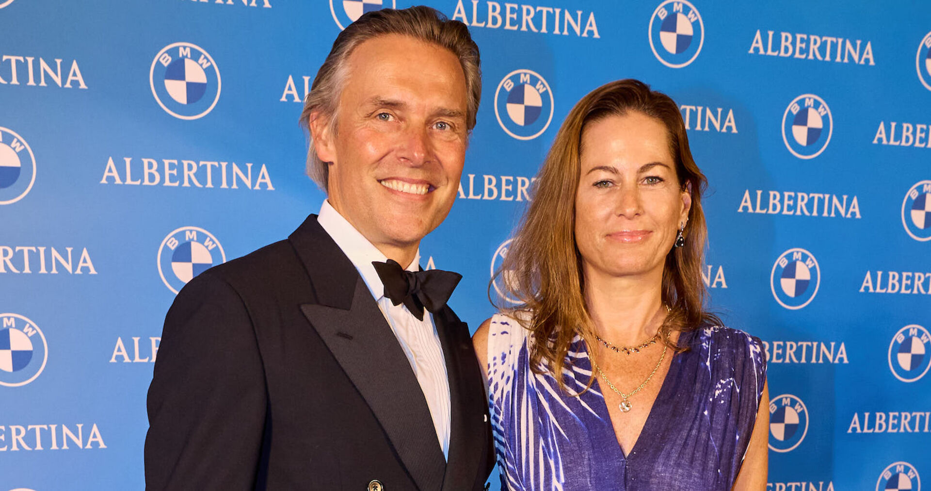 Birgit Lauda mit Partner Marcus Sieberer vor einer blauen Fotowand