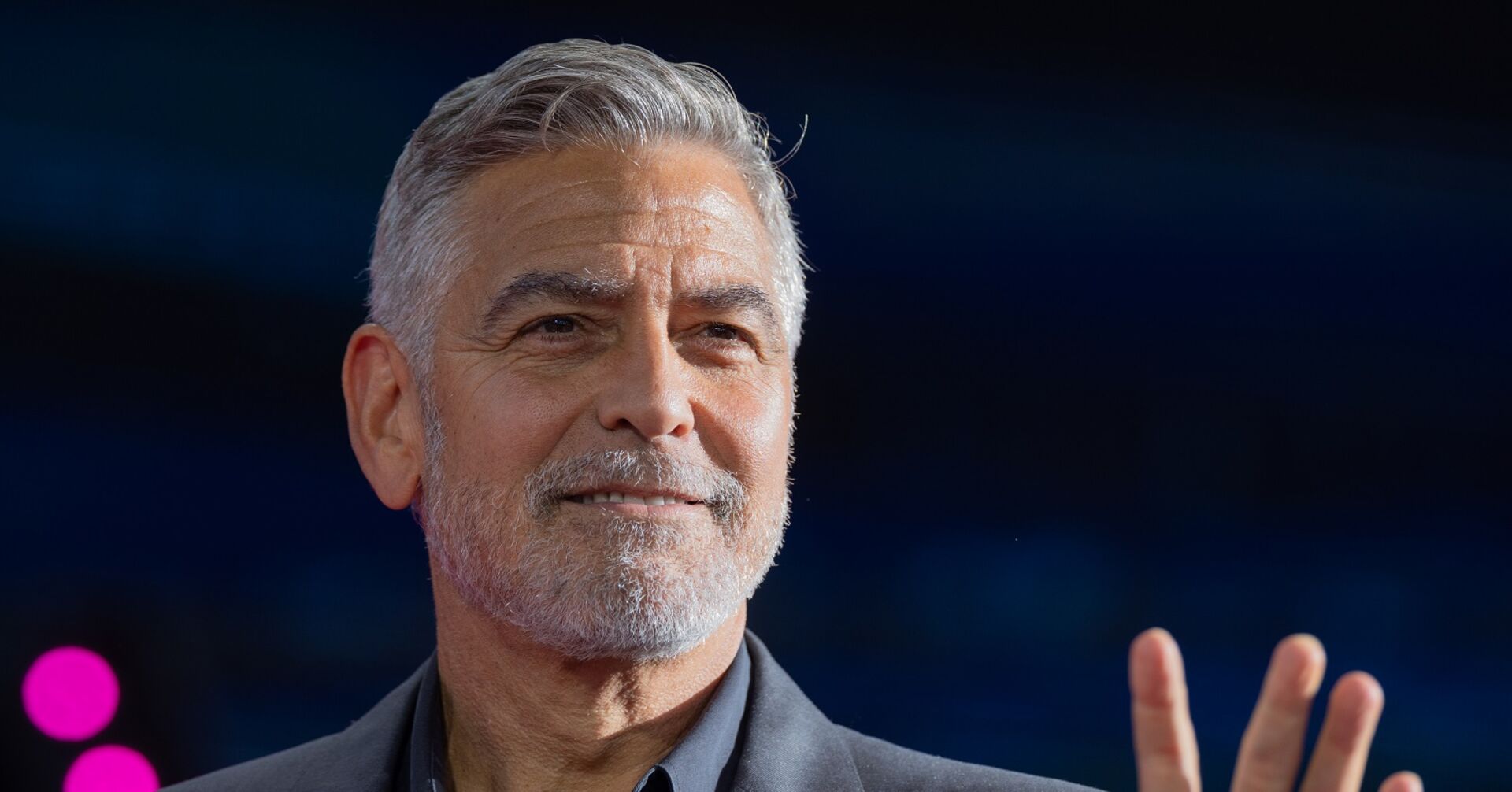 George Clooney winkt auf Podium Publikum zu