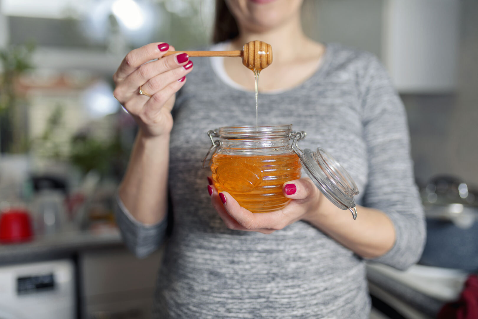 Frau hält Gefäß mit Honig in der Hand