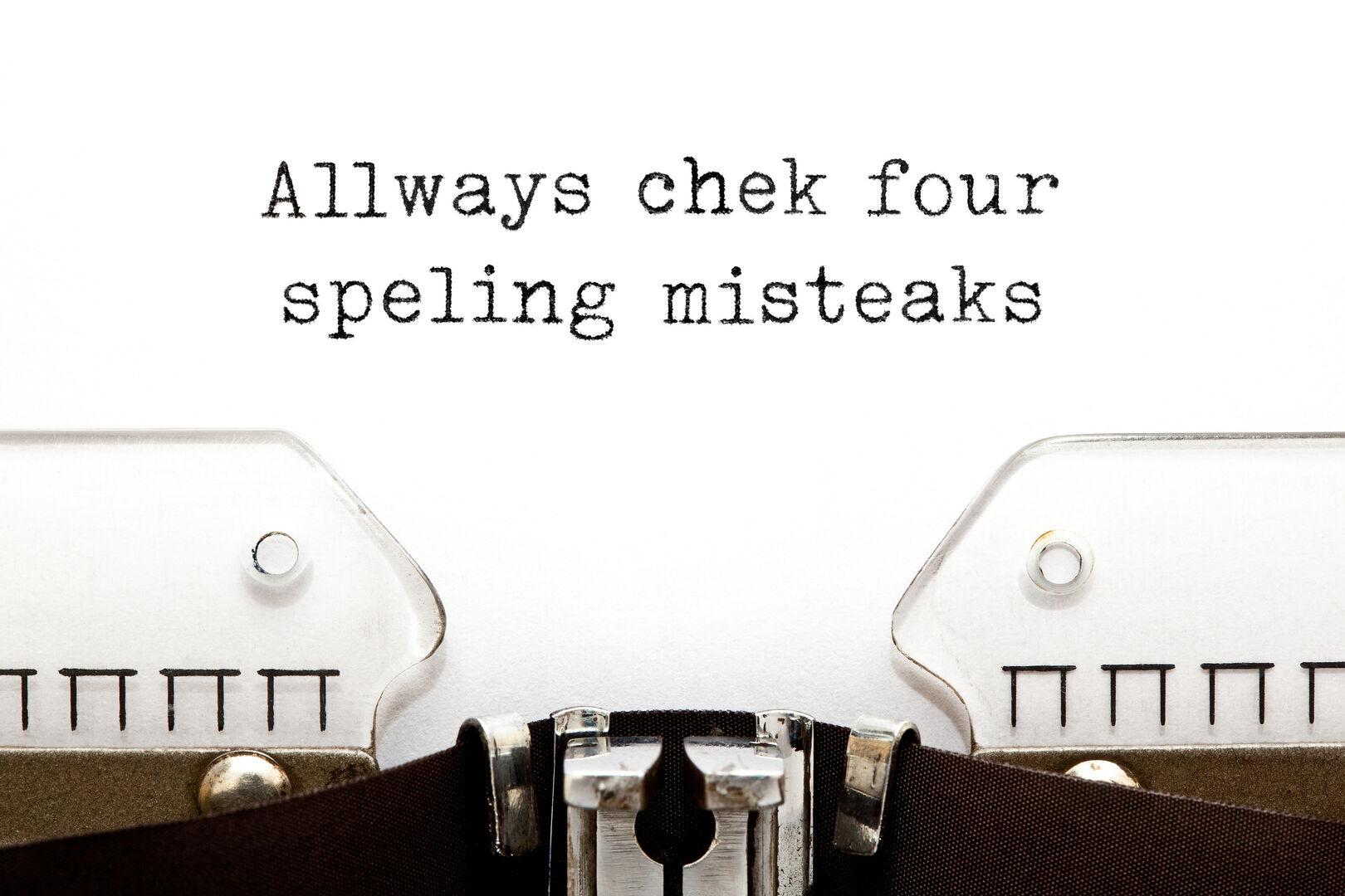 Nahaufnahme eines in eine Schreibmaschine eingespannte Blattes Papier, auf dem der Satz "Allways chek four speling misteaks" steht