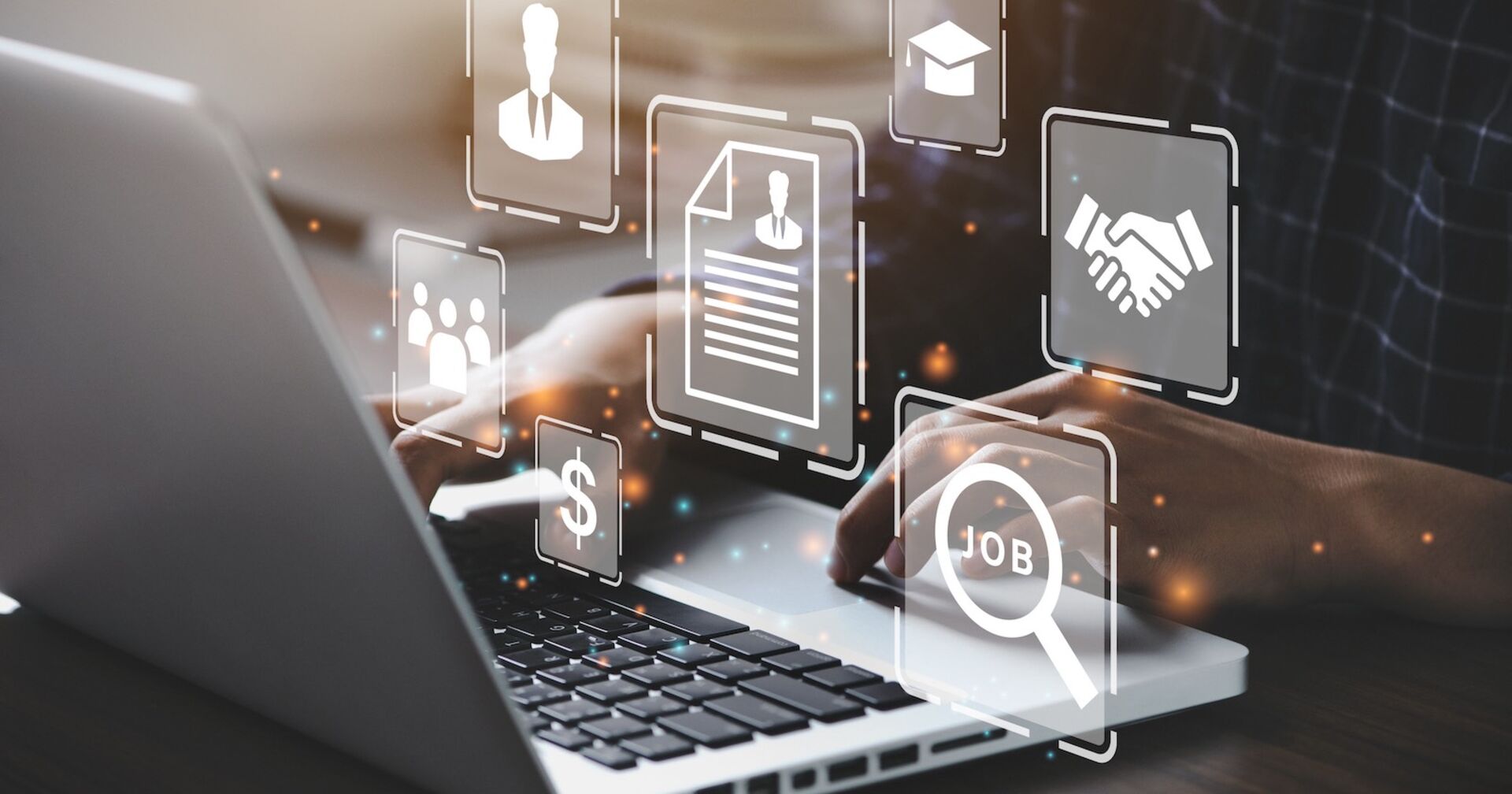 Nahaufnahme von auf einem Laptop arbeitenden Händen über die zahlreiche Symbole (z.B. Dollarzeichen und ein Lebenslauf) eingeblendet sind