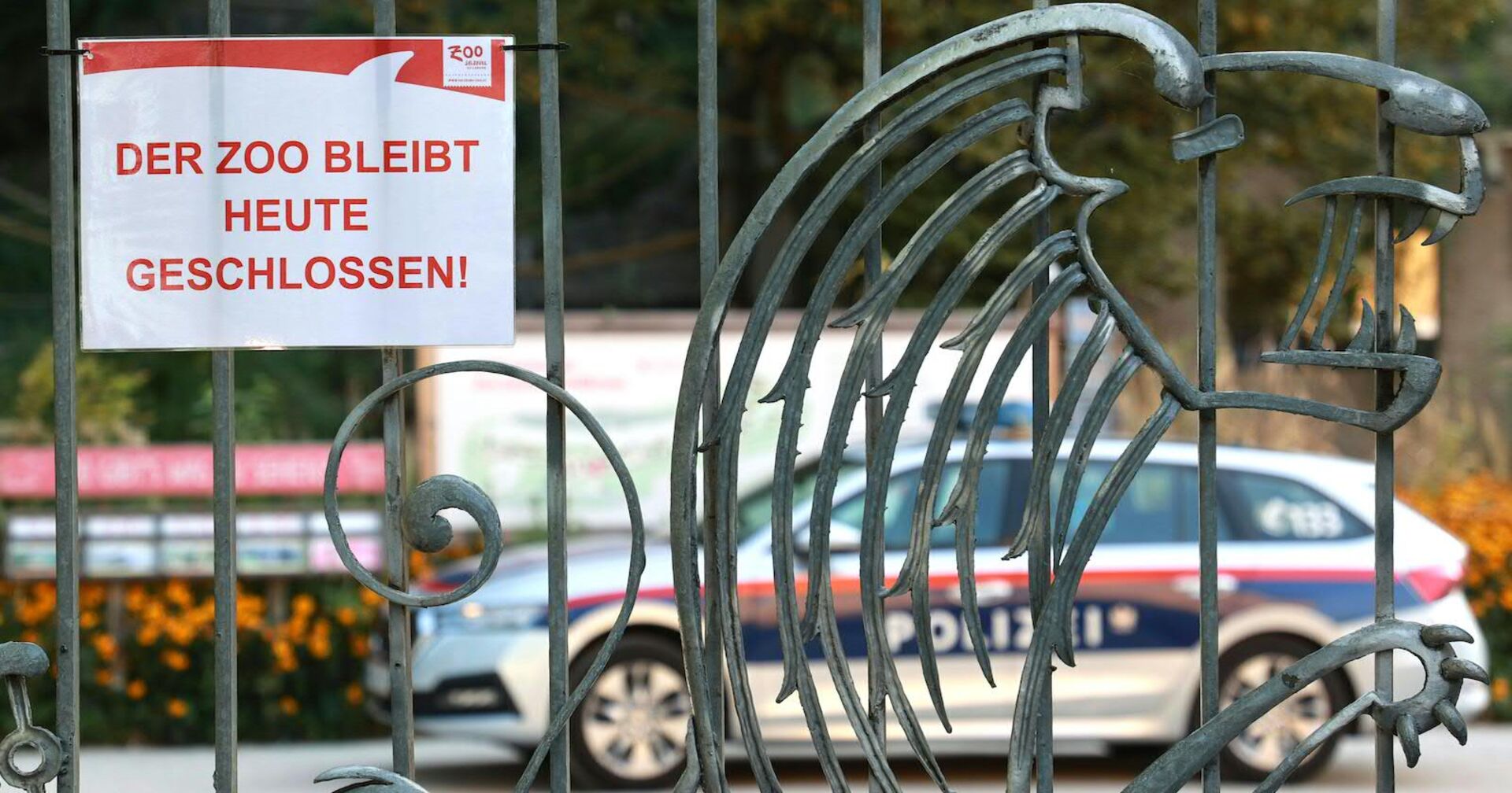 Das Eingangstor des Zoos, darauf die Info: "Der Zoo bleibt heute geschlossen!" Im Inneren der Anlage ist ein Polizeiauto geparkt.