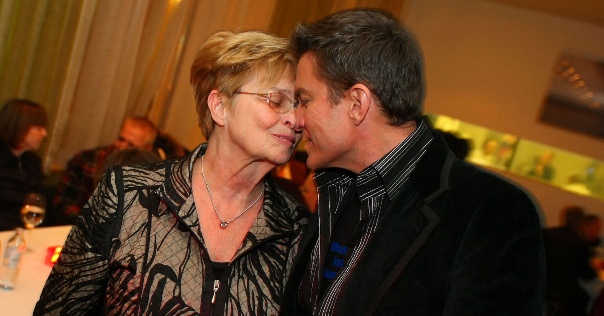 Alfons Heider und Mutter Anni Stirn an Stirn mit geschlossenen Augen in einem Raum.