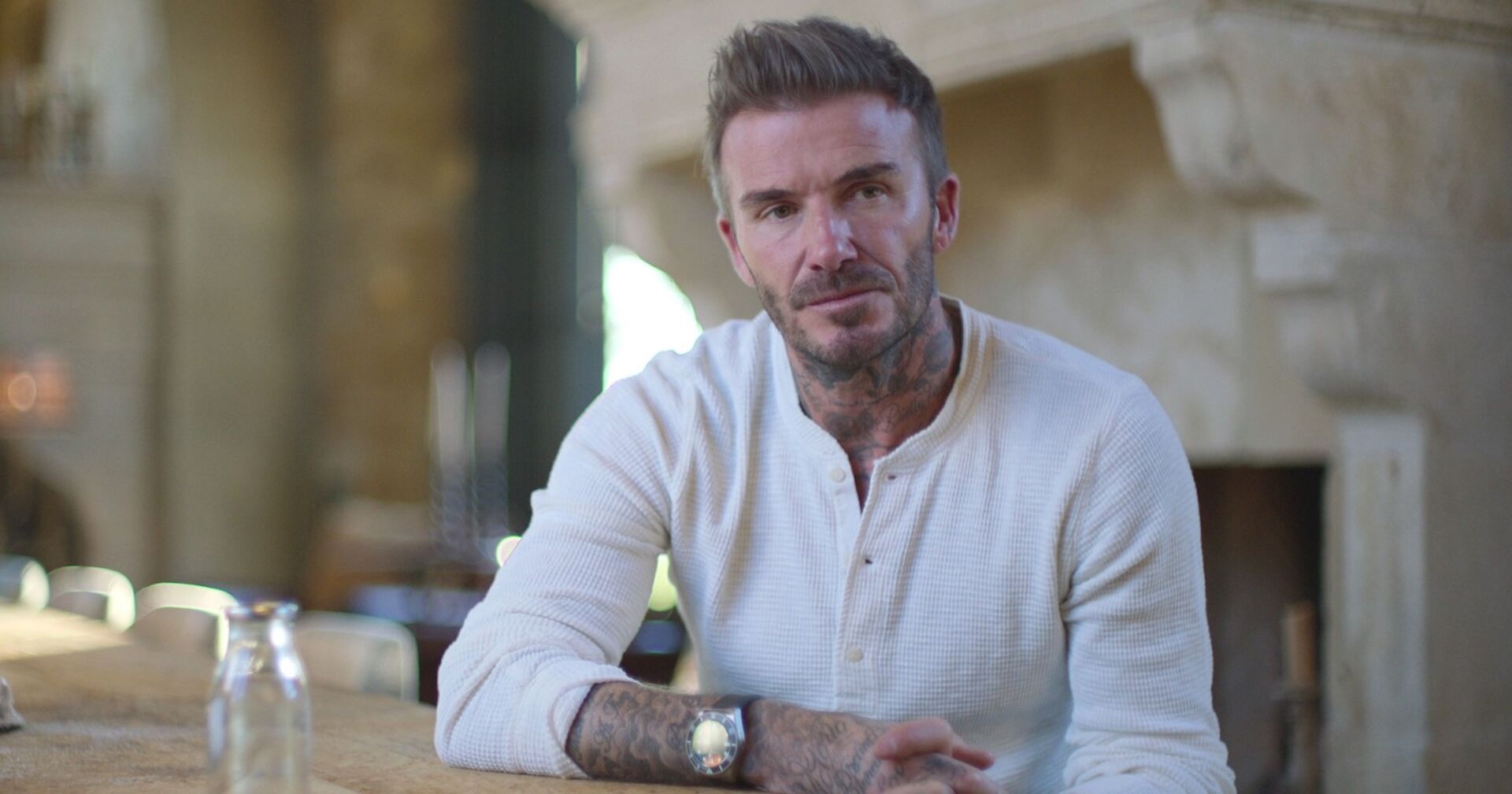 David Beckham in einem weißen Shirt. Er sitzt für ein Interview an einem Tisch.