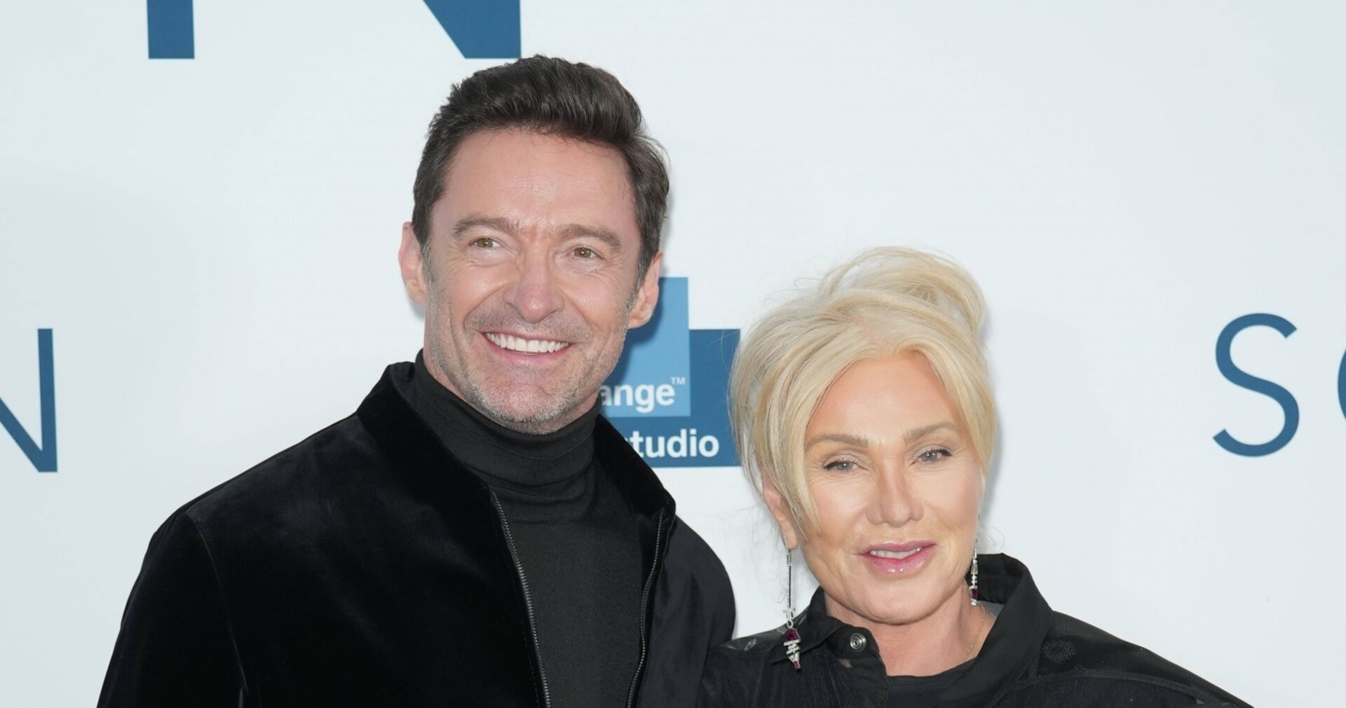 Hugh Jackman lächelt in die Kameras neben seiner Frau