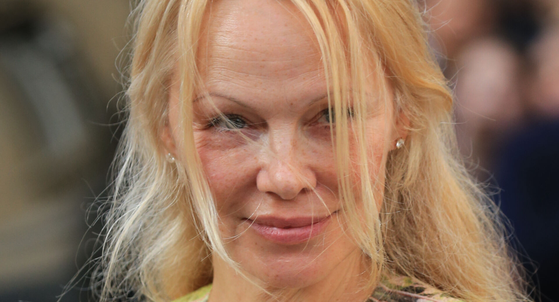 Pamela Anderson mit blonden Haaren die ihr ins Gesicht wehen.