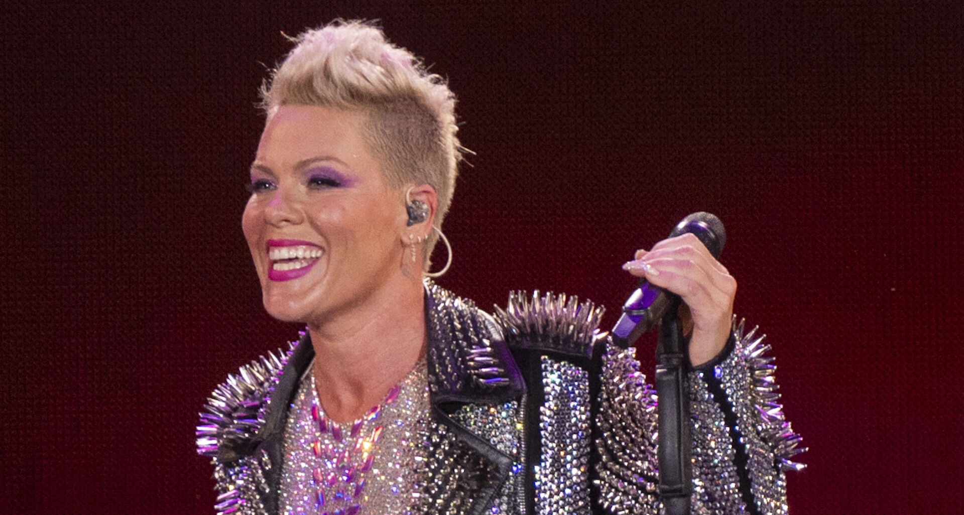 Pink hat kurze blonde Haare und eine Nietenjacke.