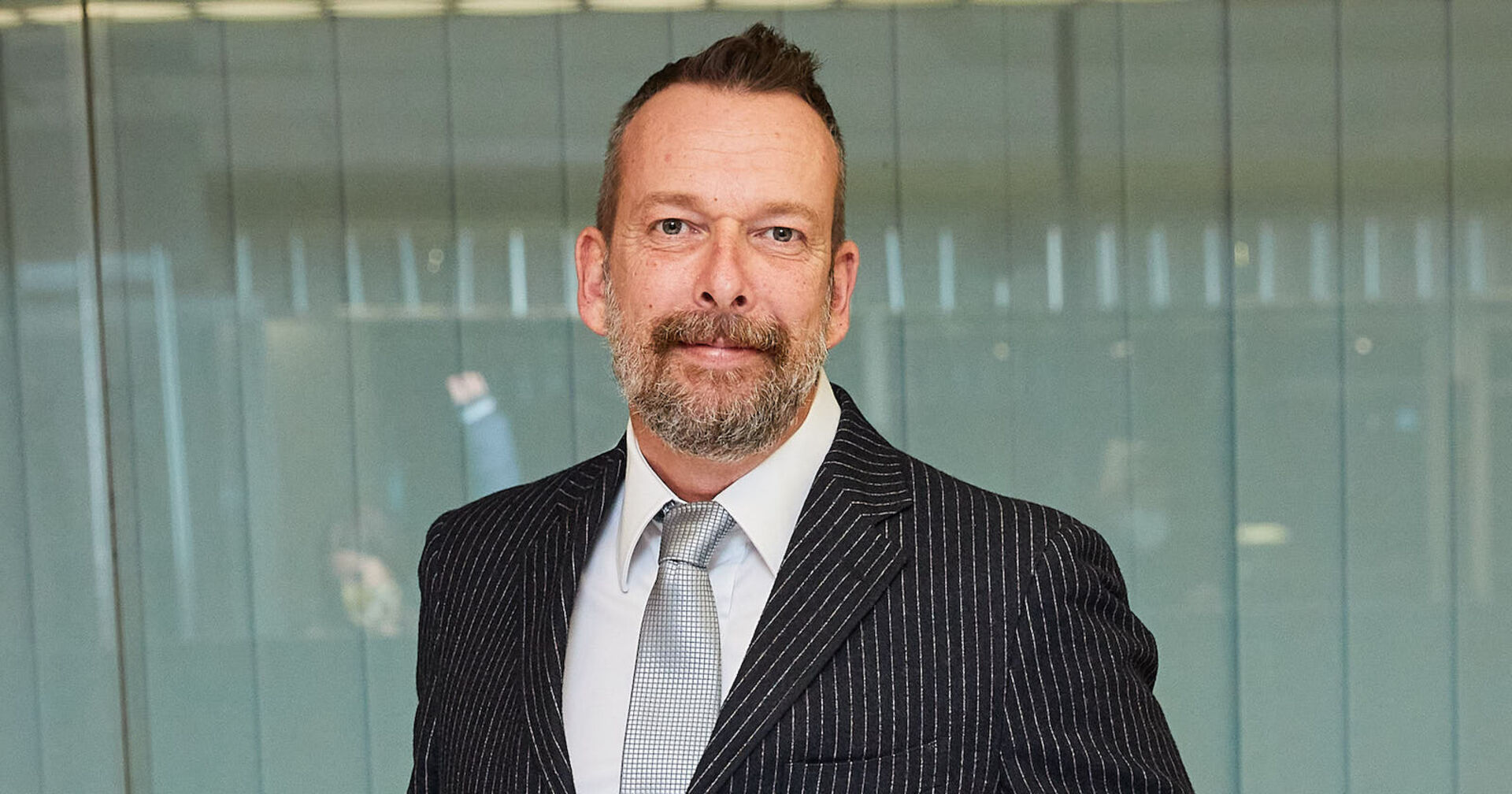 Robert Kratky trägt einen dunklen Sakko mit einer grauen Krawatte.