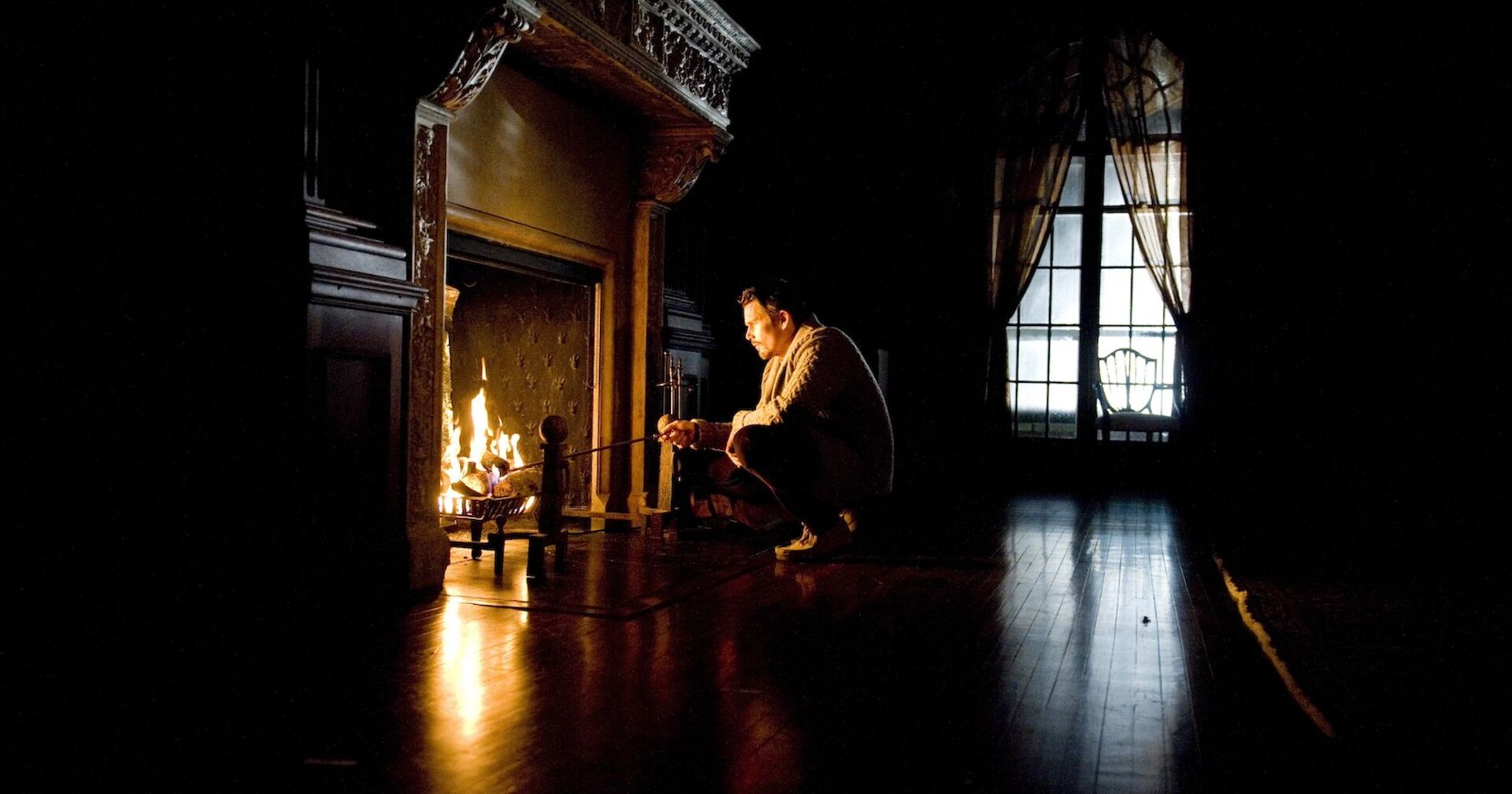Ein Mann sitzt vor einem Kamin im Dunkeln.