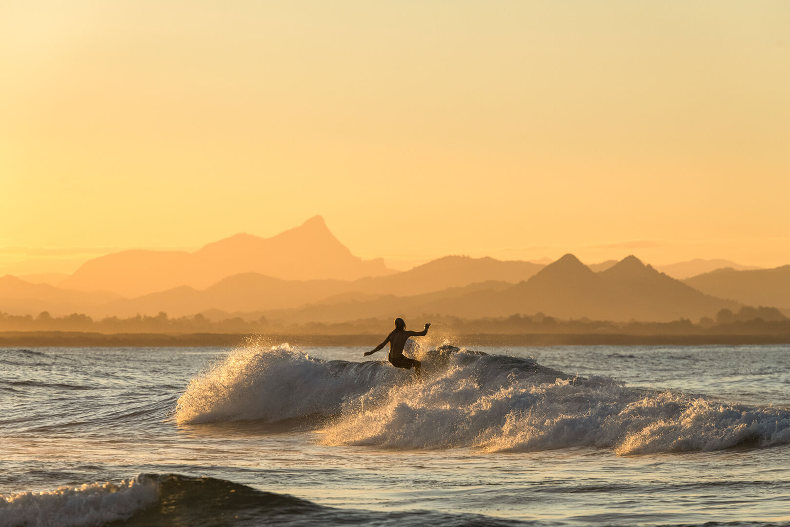Surfer auf einer Welle | Credit: iStock.com/RugliG